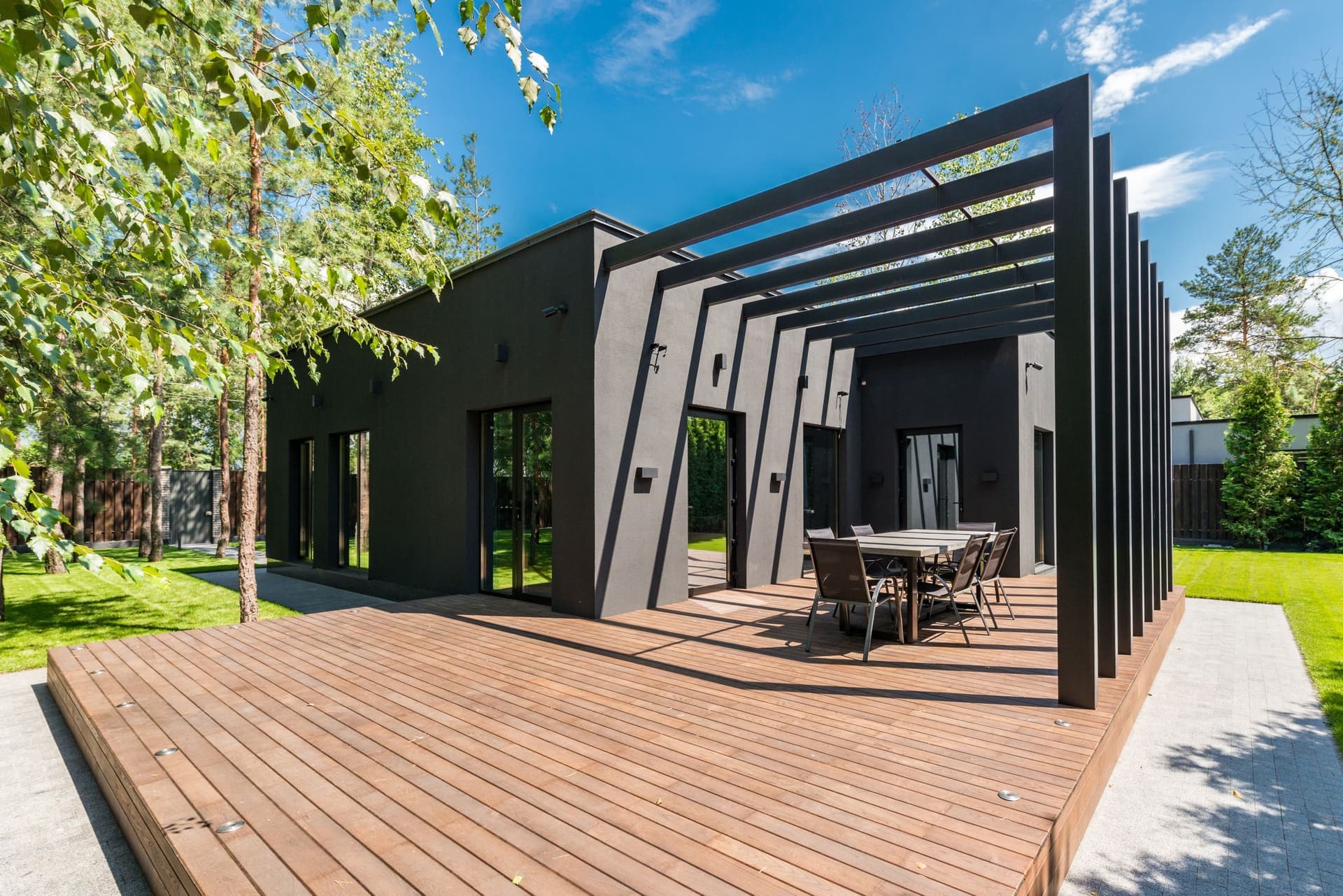 Wide custom deck with pergola beside a modern home